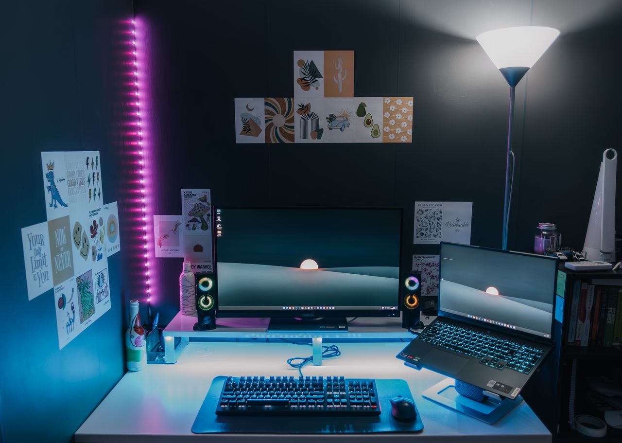 A sleek home office with dual monitors, LED lights, and creative wall art.